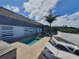 une villa avec une piscine et deux chaises longues dans l'établissement Villa Puesta de Luna, à Tazacorte