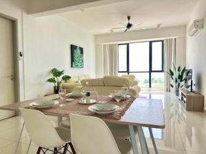 a dining room table with white chairs and a living room at Jazz Suites Seaview with Bathtub - 1603 in Tanjong Tokong