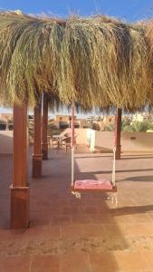 einen Pavillon mit Strohdach auf einer Terrasse in der Unterkunft Luxury Chalet in Mountain View 2 , El-Sokhna with Sea View , Pool View and Garden View Families Only in Ain Suchna