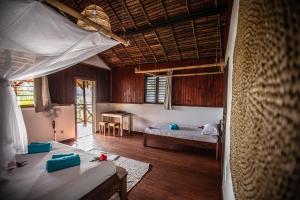 a bedroom with two beds and a table in it at Tsara Beach in Nosy Be