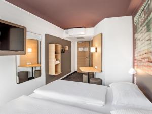 um quarto de hotel com duas camas e uma televisão em B&B Hotel Hamburg-Airport em Hamburgo