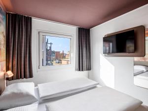 a white room with a bed and a window at B&B Hotel Hamburg-Airport in Hamburg