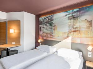a bedroom with a bed with a large painting on the wall at B&B Hotel Hamburg-Airport in Hamburg