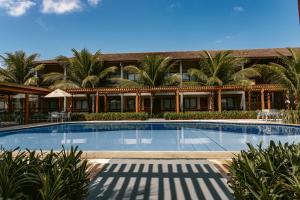 a swimming pool in front of a building with palm trees at Tabaobí Smart Hotel in Porto De Galinhas