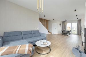 a living room with a blue couch and a table at Sunny Hills Villas - Kołobrzeg by Jantar Apartamenty in Kołobrzeg