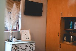 a room with a tv on the wall and a refrigerator at The Red door in Rustenburg