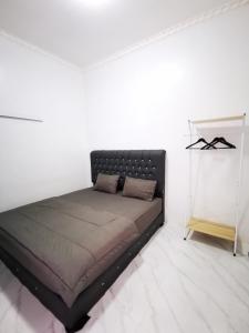 a bed in a white room with a black headboard at LOBLUS (Low Budget Luxury Stay) in Padang