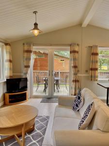 a living room with a couch and a tv and a table at Norton Plus Lodge 29 in Kingham
