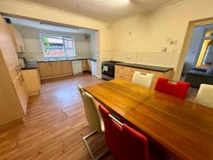 uma grande cozinha com uma mesa de madeira e cadeiras em Clare House - sleeps 14 em Bedford