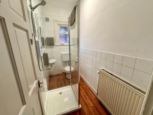 uma casa de banho com um WC e uma porta de duche em vidro. em Clare House - sleeps 14 em Bedford