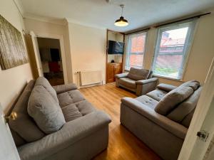 uma sala de estar com dois sofás e duas cadeiras em Clare House - sleeps 14 em Bedford