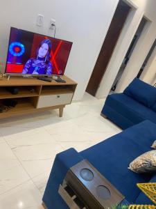 sala de estar con TV y sofá azul en Casa Arembepe 2, en Camaçari