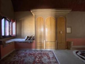 een kamer met een bed en een houten kast bij The Desert House, Luxor, Westbank in ‘Ezbet Abu Ḥabashi