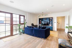 City View Spacious 2 bedroom Penthouse في لندن: غرفة معيشة مع أريكة زرقاء وتلفزيون
