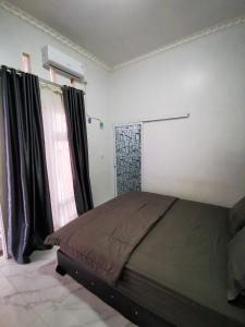 a bedroom with a large bed with black curtains at LOBLUS (Low Budget Luxury Stay) in Padang