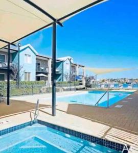 曼哲拉Apartment in Apollo Quays resort with shared Jetty的房屋前带遮阳伞的游泳池