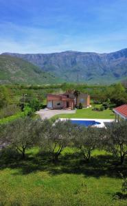 una casa en medio de un campo con montañas en el fondo en Villa Paraiso, en Mostar