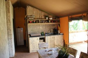 a kitchen with wooden cabinets and a table in a room at Veluwe buitenverblijf op de Glamping voor 6 personen LL55 in Putten