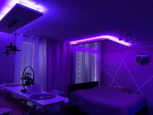 een paarse kamer met een bed en een tafel bij Love Room & Spa Jacuzzi in Fleury-les-Aubrais