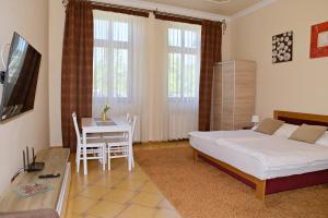 a bedroom with a bed and a table and a desk at Makotel Apartmanház in Makó