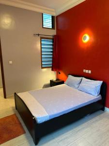 コトヌーにあるAHOUEDJI Guest House - Palais Urbain avec Balcon & Vue Merの赤い壁のベッドのある寝室