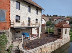 uma casa com um deque ao lado de uma massa de água em La cure du Petit Doubs em Rang