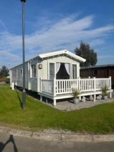 a tiny house with a porch and a white fence at Presthaven sands P&Ts home from home in Talacre