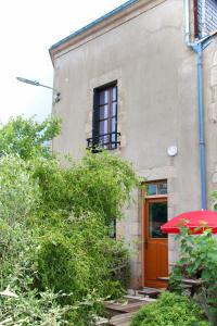 un edificio con una puerta roja y una sombrilla roja en Gîte Le Féodal 3 Etoiles, en Tiffauges