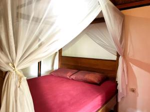 a red bed in a room with a canopy at Little Bear Bungalows in Gili Air