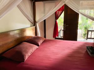 a bedroom with a large bed with a red blanket at Little Bear Bungalows in Gili Air
