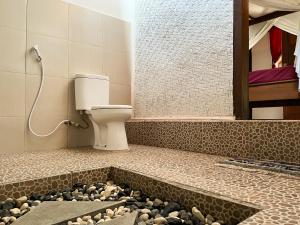 ein Badezimmer mit WC und ein paar Steinen in der Unterkunft Little Bear Bungalows in Gili Air