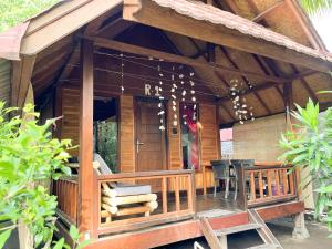 ein Holzhaus mit einer Veranda mit einem Tisch und Stühlen in der Unterkunft Little Bear Bungalows in Gili Air