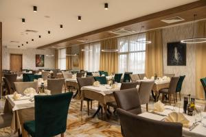 uma sala de jantar com mesas, cadeiras e janelas em Santé SPA Hotel em Velingrad