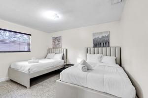 2 Betten in einem Schlafzimmer mit weißen Wänden und einem Fenster in der Unterkunft Authentic Two Bedroom Unit / Parking in Miami