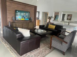 ein Wohnzimmer mit einem Sofa und einem TV in der Unterkunft Sasavona Cottage - 349 Vaal de Grace Golf Estate in Parys