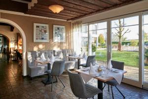a dining room with tables and chairs and windows at Kucher's Landhotel in Darscheid