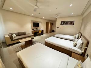 a hotel room with two beds and a couch at Siara Styles Amba Suites, Gandhinagar in Gandhinagar