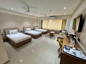 a hotel room with two beds and a couch at Siara Styles Amba Suites, Gandhinagar in Gandhinagar