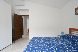 Schlafzimmer mit einem Bett mit blauer Decke in der Unterkunft Casa Bari Sardo per più famiglie in Bari Sardo
