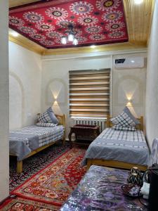 a room with two beds and a red ceiling at Khiva Rajab Ota in Khiva