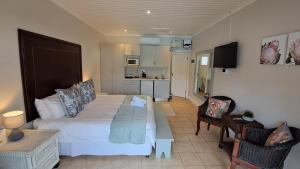 a bedroom with a large bed and a kitchen at The Dunes Studio 11 in Plettenberg Bay