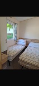 two beds in a room with a window at Paradise Holiday home in Lytchett Minster