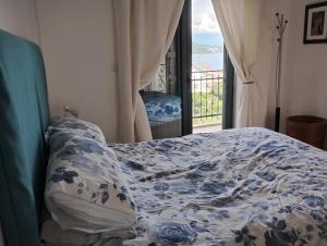 Una cama con un edredón azul y blanco y una ventana. en Monteview Duplex, en Herceg-Novi