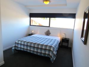 a bedroom with a bed with a checkered blanket at Central Apartment in Hanmer Springs