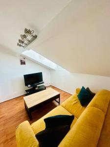 马恩河畔莱佩尔勒Studio Le Cocon détente proche Paris Disney的客厅里有一张黄色的沙发和一张桌子