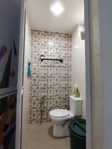 een badkamer met een toilet en een tegelwand bij Sri MaLati Homestay and Event Space in Balik Pulau