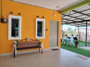 uma parede amarela com um banco e um pátio em Sri MaLati Homestay and Event Space em Balik Pulau