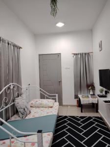 a small bedroom with a bed and a tv at Sri MaLati Homestay and Event Space in Balik Pulau