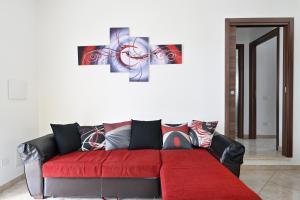 ein Wohnzimmer mit einer roten Couch mit einer Uhr an der Wand in der Unterkunft Casa Bari Sardo per più famiglie in Bari Sardo