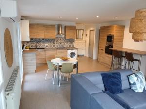 ein Wohnzimmer und eine Küche mit einem blauen Sofa und einem Tisch in der Unterkunft Appartement Confort Miribel 80m2 in Miribel